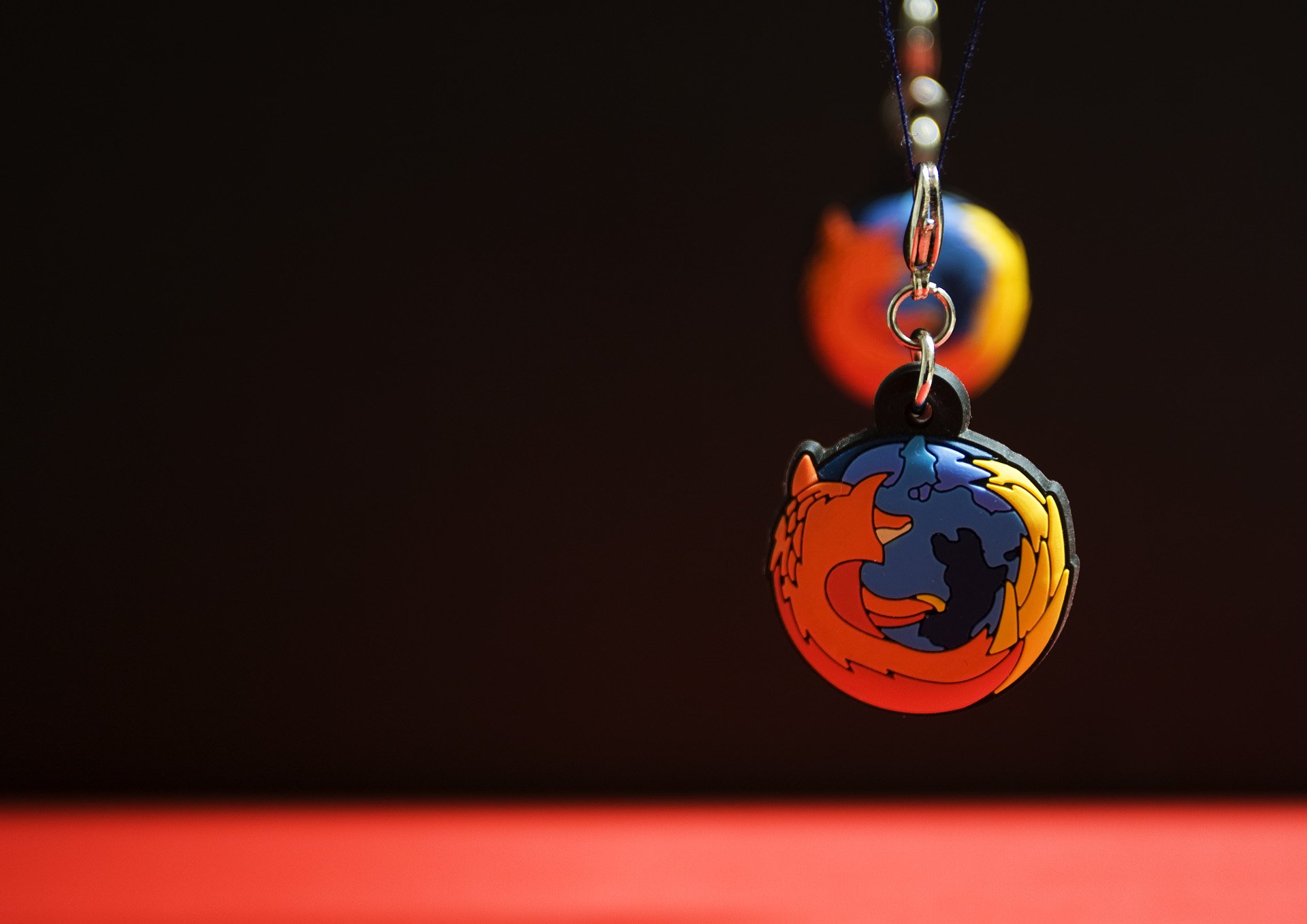 HD PC desktop wallpaper featuring a close-up of a Firefox browser logo keychain, symbolizing internet technology by Mozilla against a dark background.