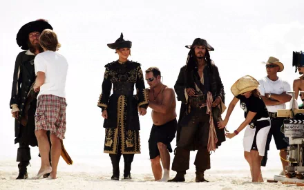 Behind-the-scenes moment from *Pirates of the Caribbean: At World's End* featuring Jack Sparrow, Hector Barbossa, and Elizabeth Swann, showcasing film production and character costumes.