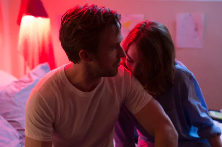 HD desktop wallpaper featuring Emma Stone and Ryan Gosling in a scene from the movie La La Land. The image captures a tender moment between the two under soft, colorful lighting.