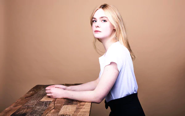 Elle Fanning, American actress with blonde hair and green eyes, poses against a plain beige background in this 8K Ultra HD desktop wallpaper.