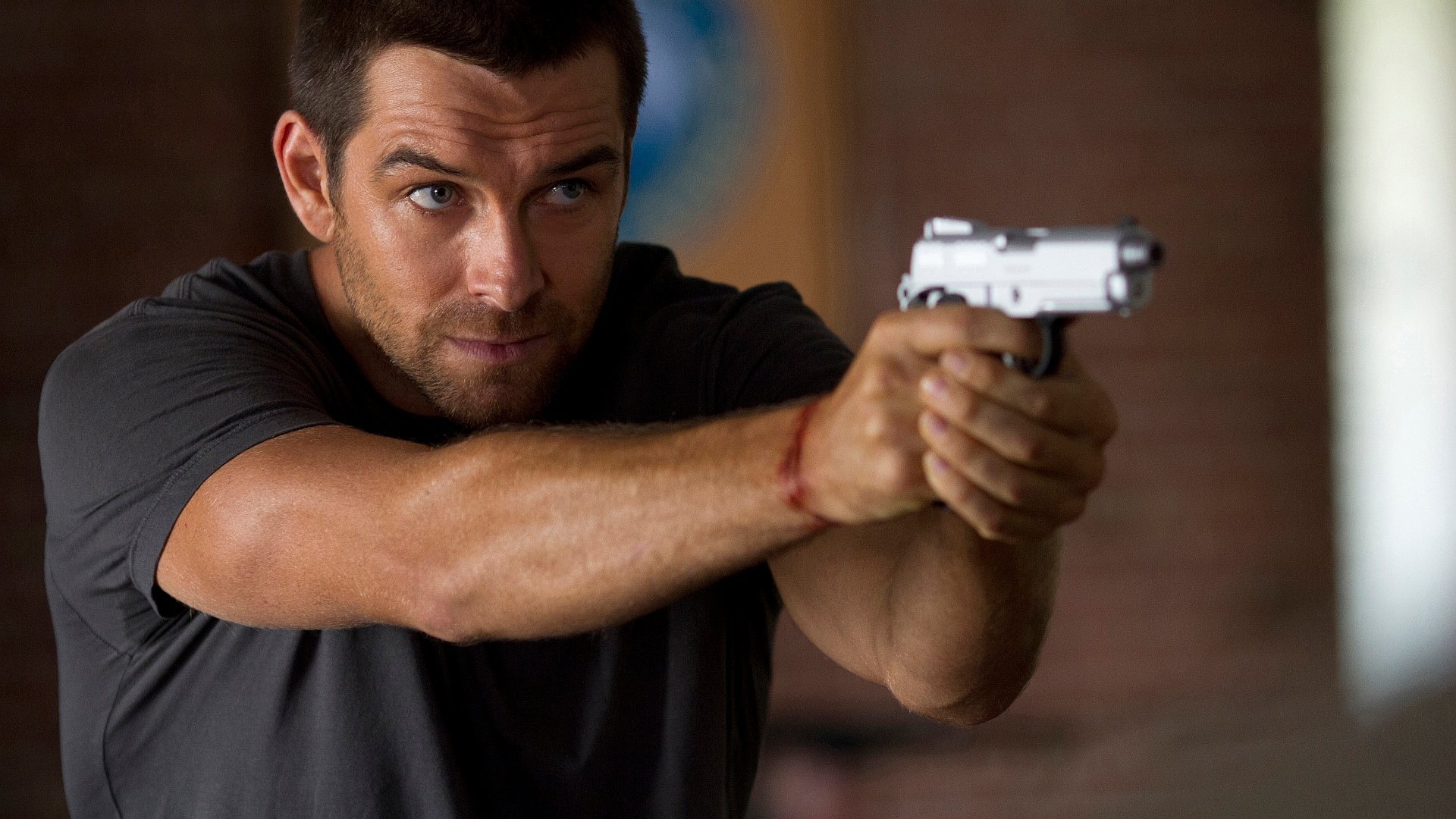 HD desktop wallpaper featuring a tense scene from the TV show Banshee, with a focused character aiming a handgun.