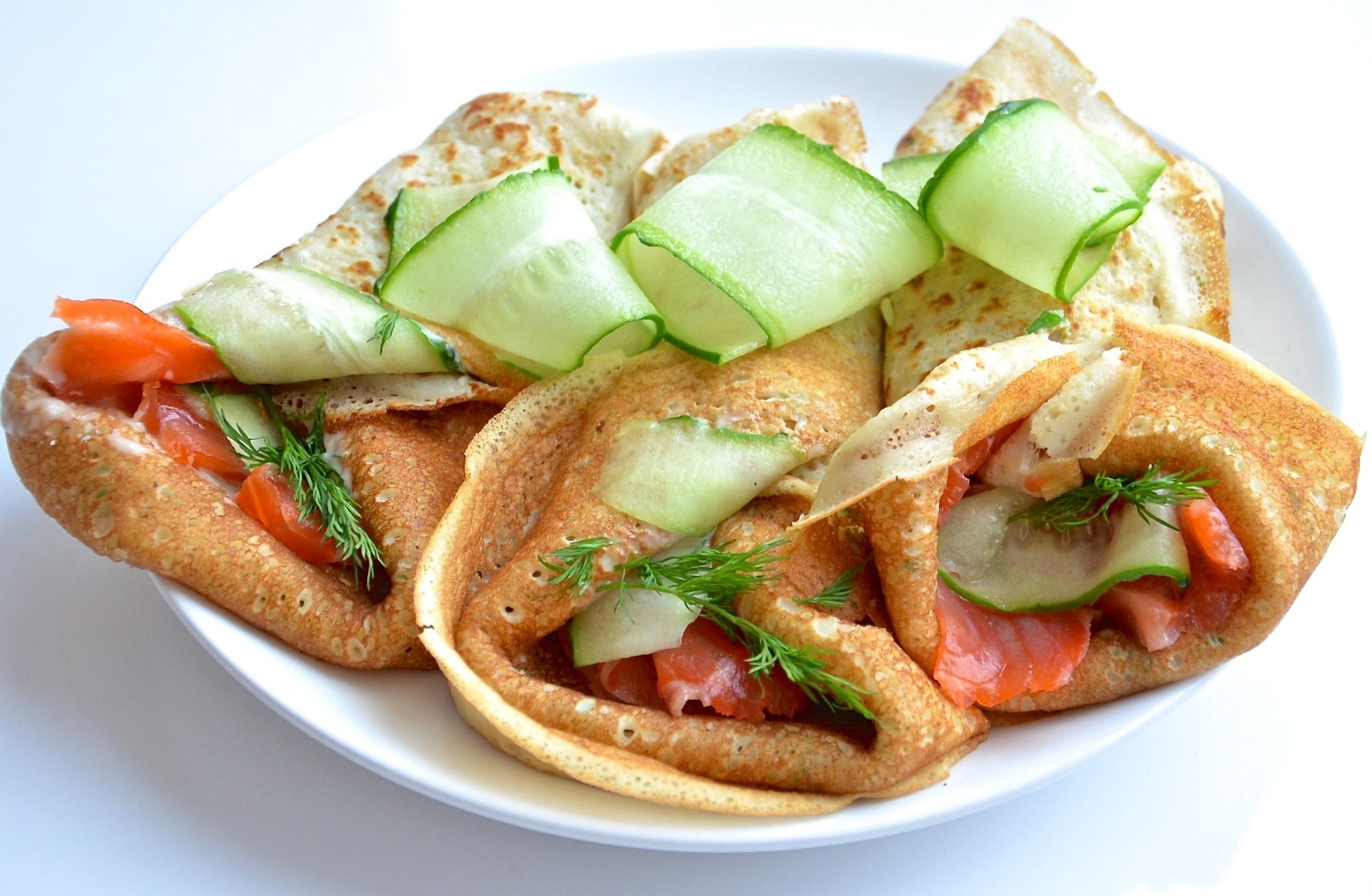 HD PC desktop wallpaper background — food: three crêpes filled with smoked salmon, cucumber ribbons and dill on a white plate, bright close-up.