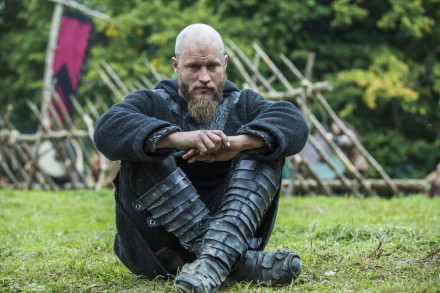 HD PC desktop wallpaper featuring Ragnar Lothbrok from the TV show Vikings (2013), seated outdoors in traditional Viking attire with a contemplative expression.
