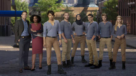 HD desktop wallpaper of the Quantico TV show cast standing together on a city street — an ensemble of agents in uniform, confident poses and urban backdrop.