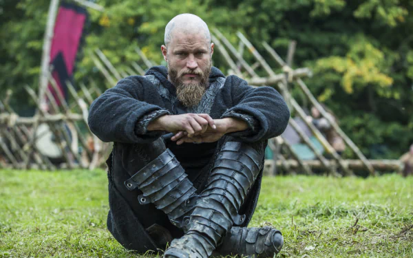 HD PC desktop wallpaper featuring Ragnar Lothbrok from the TV show Vikings (2013), seated outdoors in traditional Viking attire with a contemplative expression.