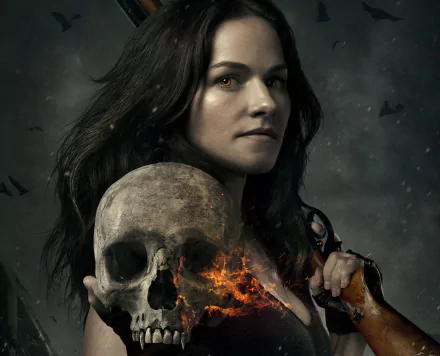 HD desktop wallpaper of a dark-haired woman from the TV show Van Helsing, holding a skull with dark clouds and flying bats in the background.