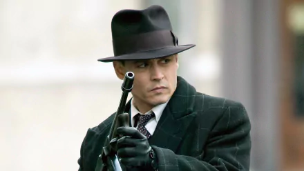 Johnny Depp as a character in the movie Public Enemies, dressed in a dark coat and fedora, holding a gun, featured in an HD PC desktop wallpaper.