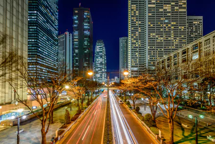 Nighttime time-lapse view of Tokyo’s cityscape featuring skyscrapers and a busy highway with light trails, captured in high definition as a PC desktop wallpaper.