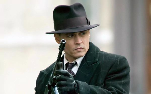 Johnny Depp as a character in the movie Public Enemies, dressed in a dark coat and fedora, holding a gun, featured in an HD PC desktop wallpaper.