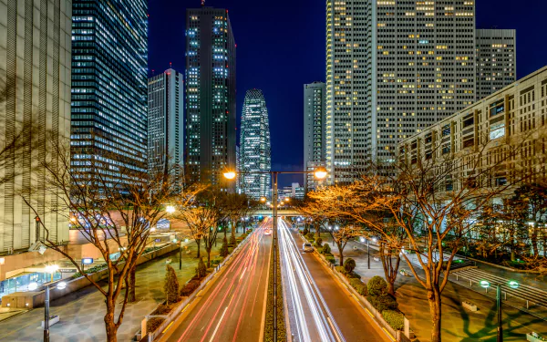 Nighttime time-lapse view of Tokyo’s cityscape featuring skyscrapers and a busy highway with light trails, captured in high definition as a PC desktop wallpaper.