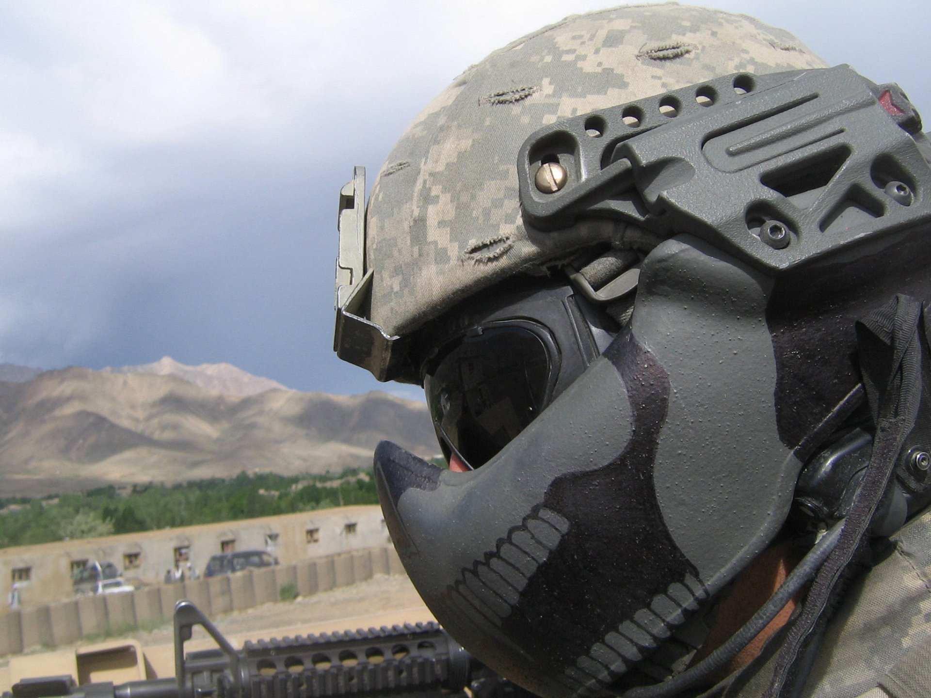 HD desktop wallpaper featuring a close-up of a soldier in tactical gear with a mountainous landscape in the background. Tagged with: military, soldier.