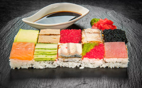 5K Ultra HD PC desktop wallpaper of assorted sushi mosaic on rice — colorful fish, roe, cucumber and tamago squares on a slate board with soy sauce, pickled ginger and wasabi.