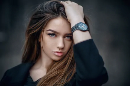 HD desktop wallpaper of a brunette woman model with striking blue eyes, posing with her hand in her hair against a blurred dark background.
