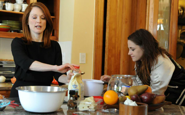 HD PC wallpaper featuring Kristen Stewart and Julianne Moore in a scene from the movie Still Alice, set in a kitchen with fruit and baking bowls on the counter.
