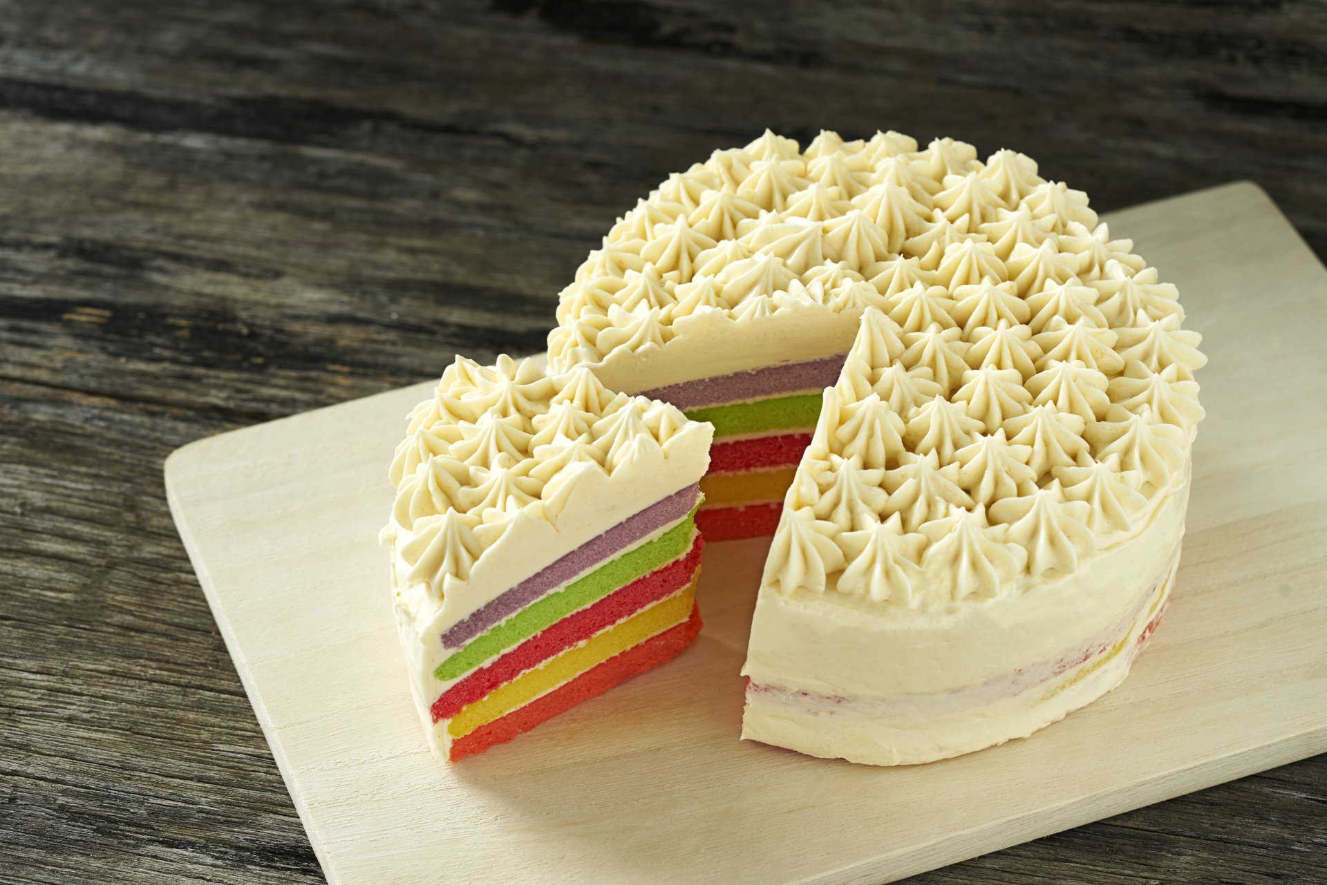 A multi-layered colorful pastry cake with cream frosting on a wooden board, captured in 8K Ultra HD for PC desktop wallpaper and background.