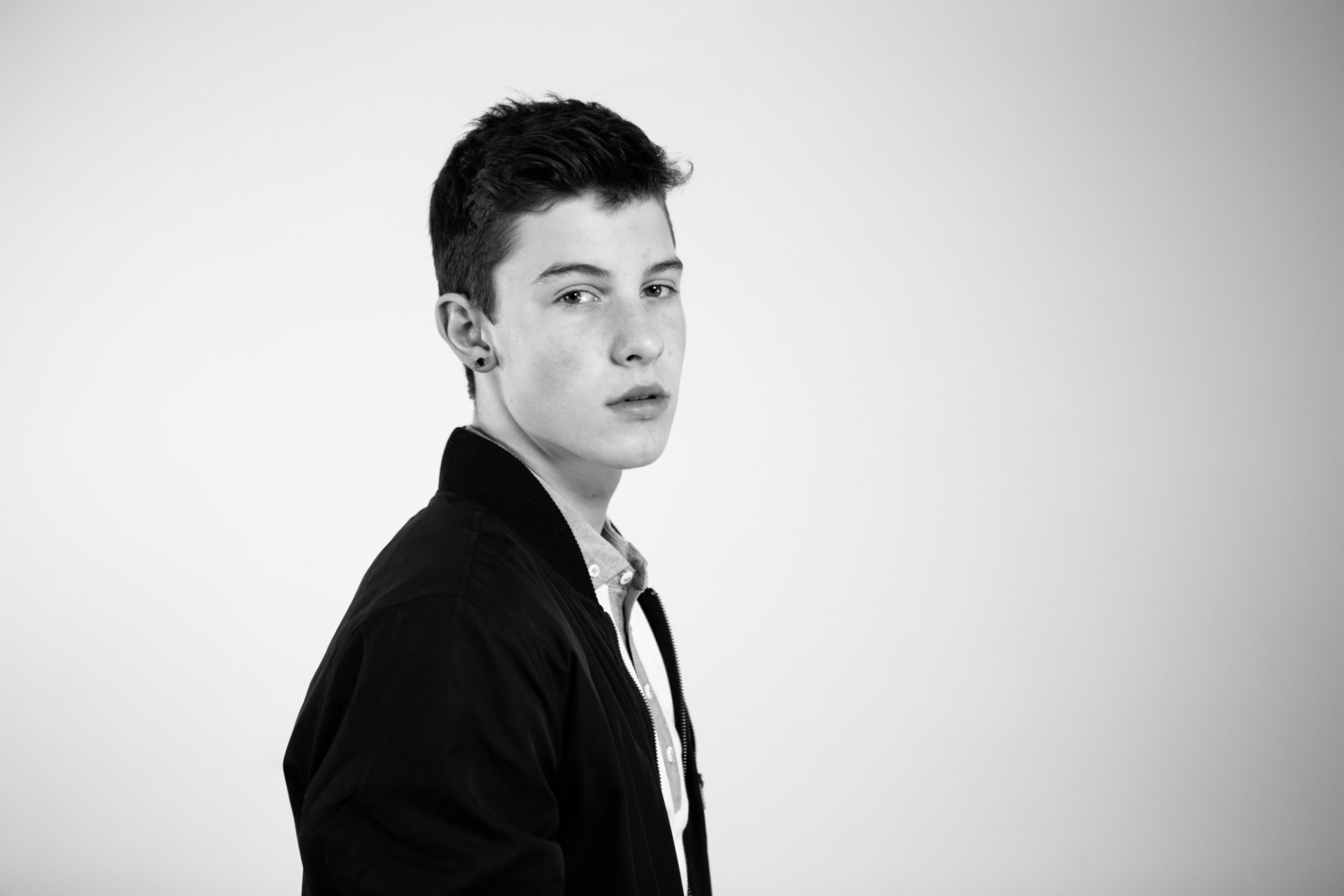 Black and white HD desktop wallpaper featuring a portrait of Shawn Mendes in a black jacket, white shirt, looking to the side.