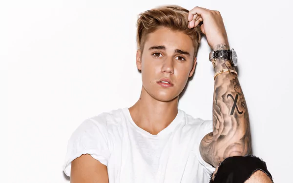 HD desktop wallpaper featuring a portrait of a young man with tattoos posing confidently against a white background.
