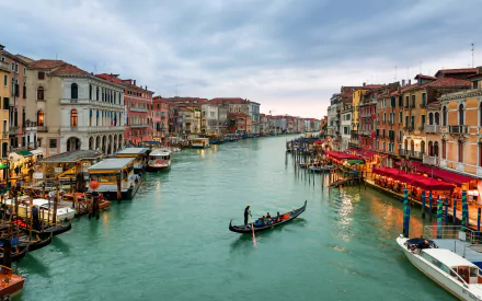 A vibrant view of Venice's Grand Canal with historic architecture, colorful buildings, and a gondola gliding through the water, showcasing iconic Italian man-made beauty.