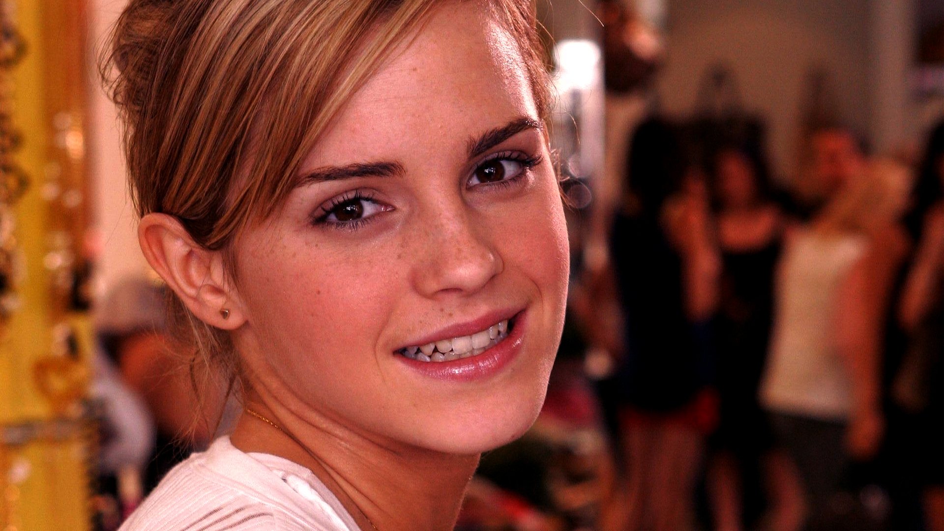 Close-up portrait of Emma Watson with a warm smile, set against a softly blurred background. This HD image serves as an eye-catching desktop wallpaper and background.