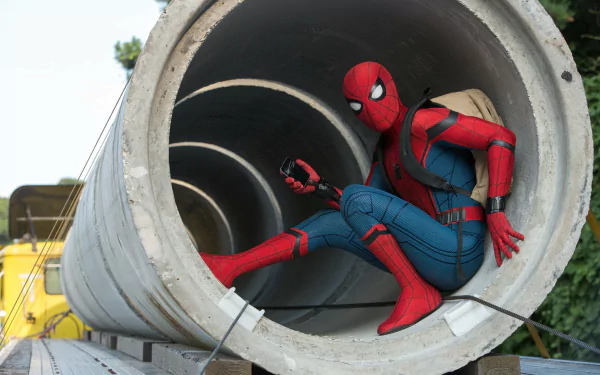 HD wallpaper featuring Spider-Man crouched inside a large concrete tube, with a backpack and a smartphone, from the movie Spider-Man: Homecoming.