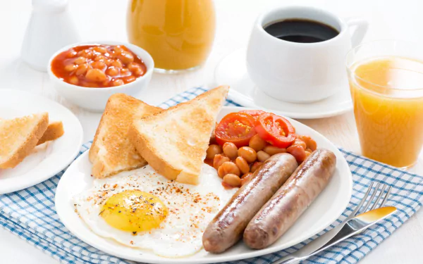 A colorful breakfast spread featuring toast with jam, fried egg, sausages, baked beans, coffee, and orange juice on a checkered tablecloth, captured as an HD PC desktop wallpaper.