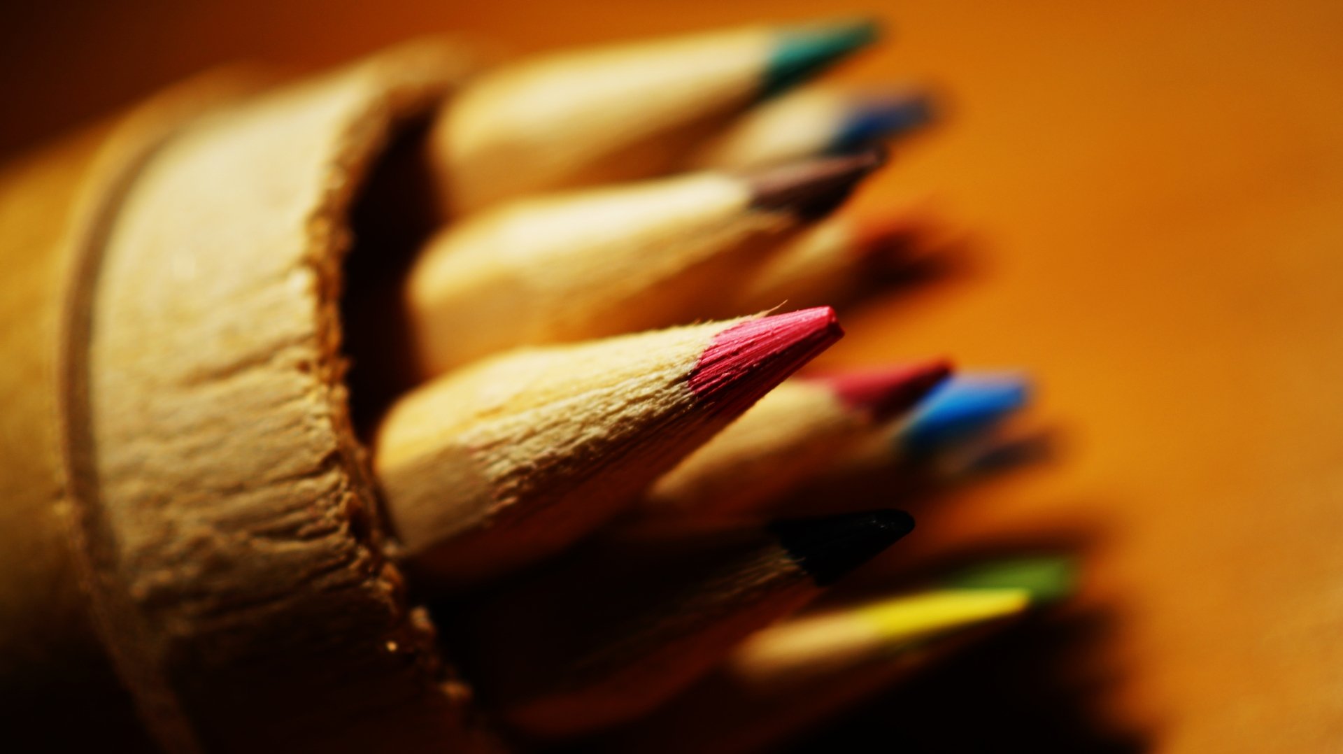 Close-up photography of colored pencil tips in a holder with warm bokeh and vivid colors — 5K Ultra HD PC desktop wallpaper and background.