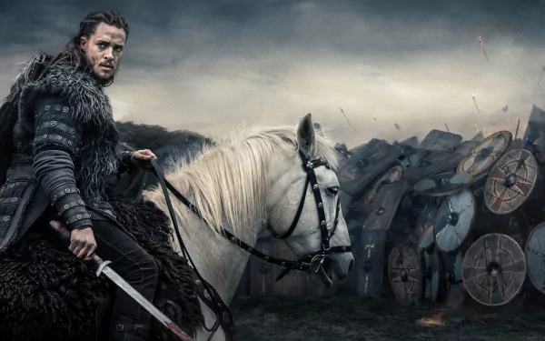 A warrior from The Last Kingdom TV show rides a white horse in front of a battlefield, featured in a 4K Ultra HD PC desktop wallpaper and background.
