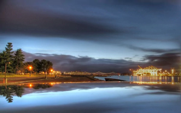 HD desktop wallpaper of a tranquil river scene at dusk with a dock, calm water reflecting the sky, and softly lit nature along the shore.