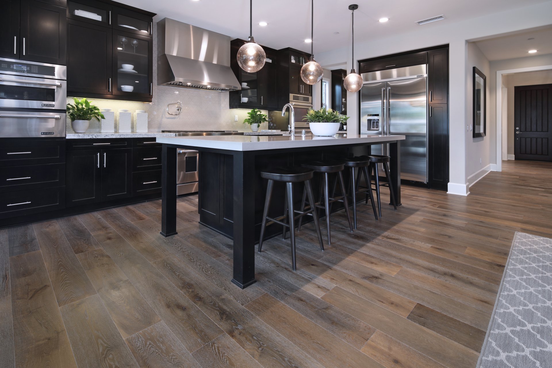 5K Ultra HD PC desktop wallpaper showing a modern man-made kitchen room with dark cabinetry, central island, bar stools, stainless appliances and wide hardwood floors.