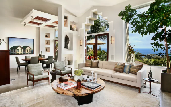 Bright living room with modern man-made furniture, large windows overlooking greenery and ocean, and stylish decor, captured as an HD PC desktop wallpaper and background.
