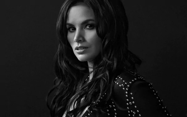 Monochrome HD PC desktop wallpaper of a celebrity actress in black-and-white, long dark hair and studded jacket, gazing confidently against a dark studio background.