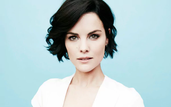 HD PC desktop wallpaper: close-up portrait of a woman with short dark hair, direct gaze and light makeup against a pale blue background.