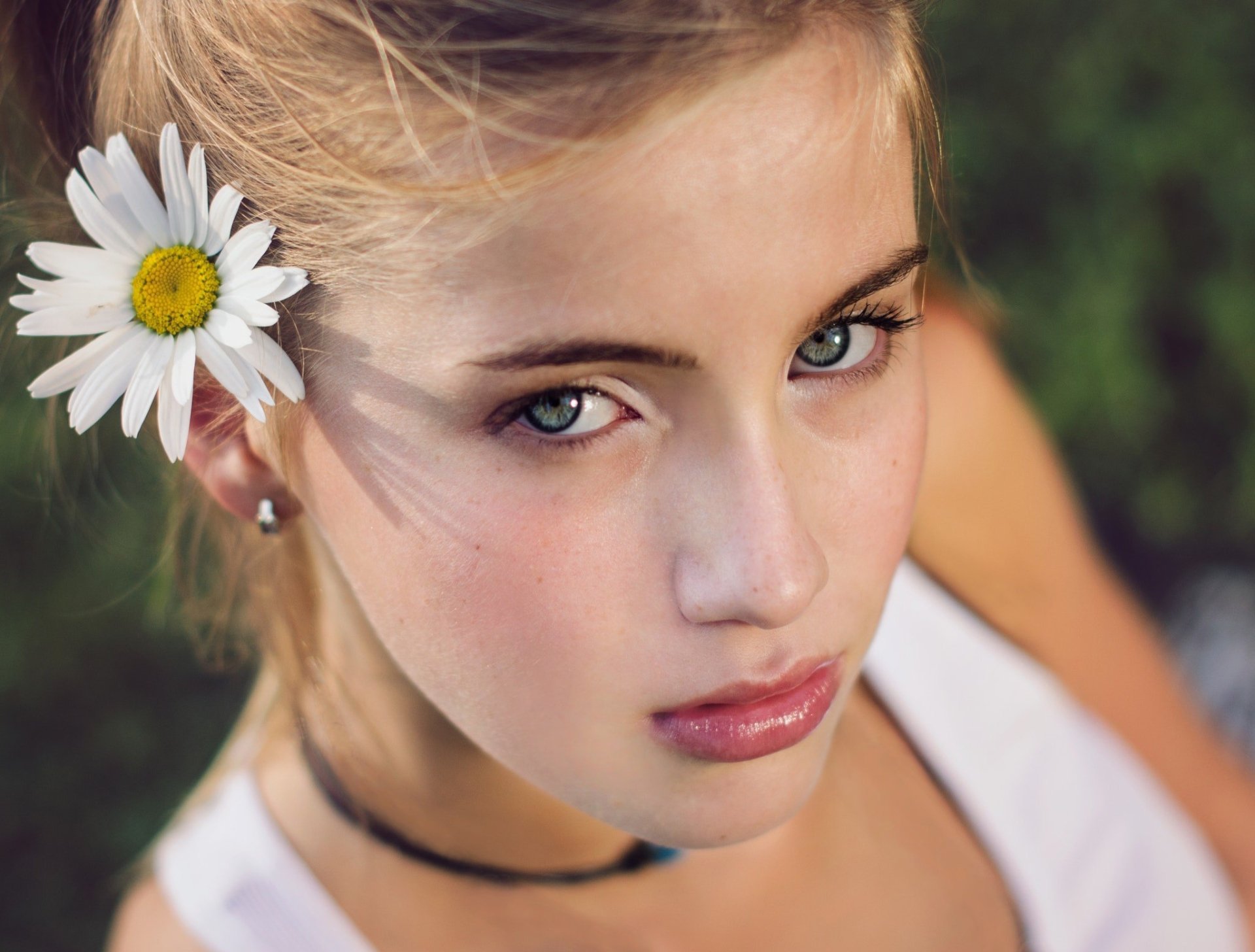 HD desktop wallpaper: close-up portrait of a blonde woman model with blue eyes, a daisy tucked behind her ear, soft-focus background.