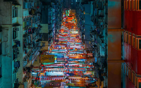 Vibrant night view of a bustling Hong Kong street market lined with buildings, showcasing colorful lights and lively city life in this HD desktop wallpaper.