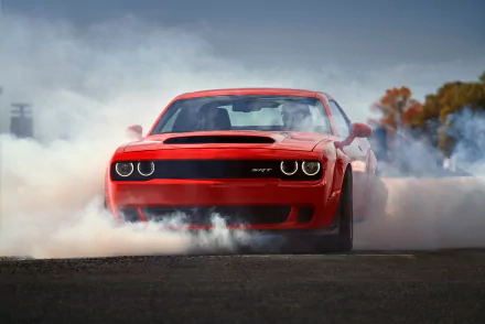 A red Dodge Challenger SRT Demon muscle car performing a burnout, surrounded by tire smoke, featured as an HD PC desktop wallpaper and background.