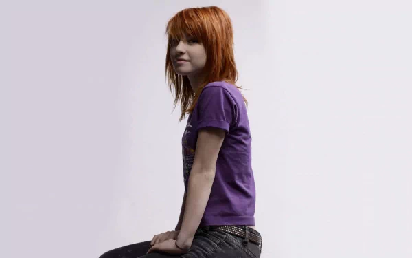 HD PC desktop wallpaper featuring Hayley Williams of Paramore, showcasing her red hair and casual purple outfit against a simple light background.