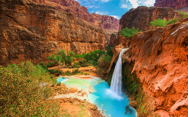 HD PC desktop wallpaper showing Havasu Falls cascading into a turquoise pool in a red-rock canyon, surrounded by lush vegetation and a vivid blue sky.
