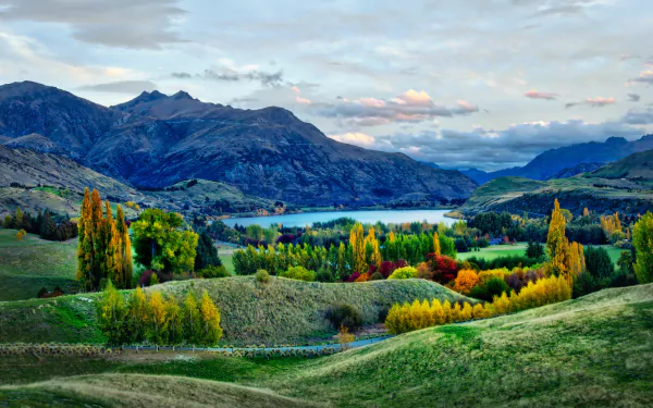 Vibrant fall landscape featuring a serene lake surrounded by hills and mountains under a cloudy sky, captured in stunning 8K Ultra HD for PC desktop background.