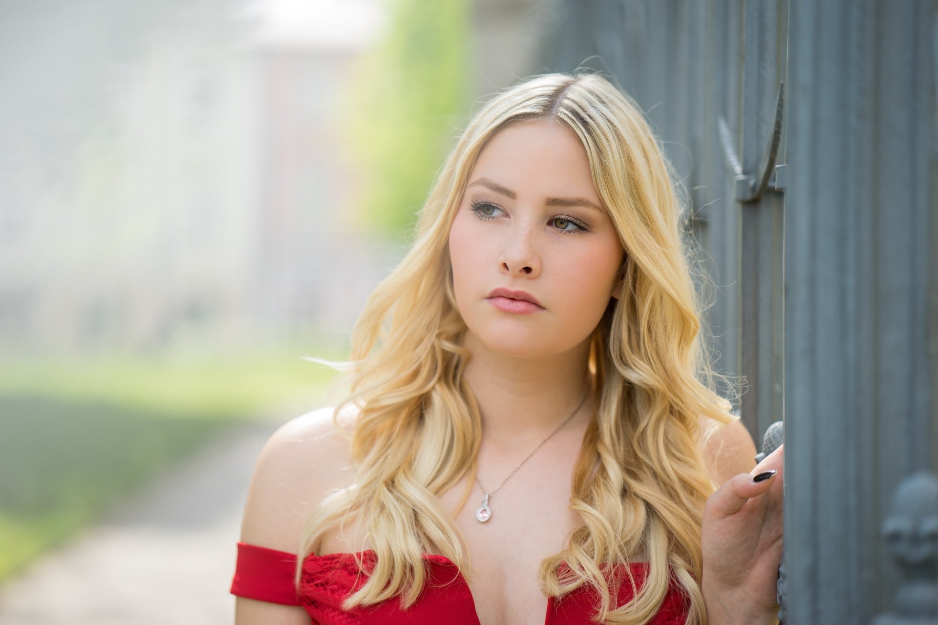Close-up of a blonde woman model with a soft depth of field, captured in 4K Ultra HD, featuring a serene expression against a blurred outdoor background.