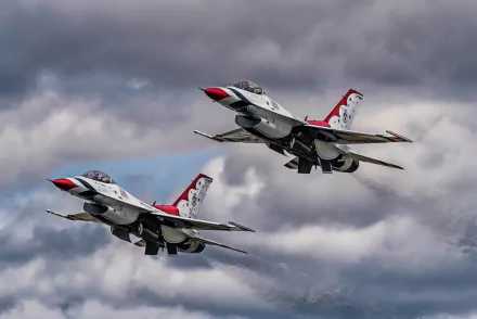 Two United States Air Force Thunderbirds General Dynamics F-16 Fighting Falcon jet fighters flying against a cloudy sky in this HD desktop wallpaper.