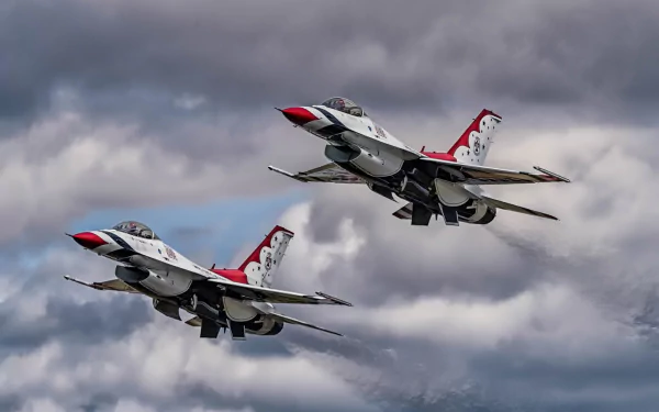 Two United States Air Force Thunderbirds General Dynamics F-16 Fighting Falcon jet fighters flying against a cloudy sky in this HD desktop wallpaper.