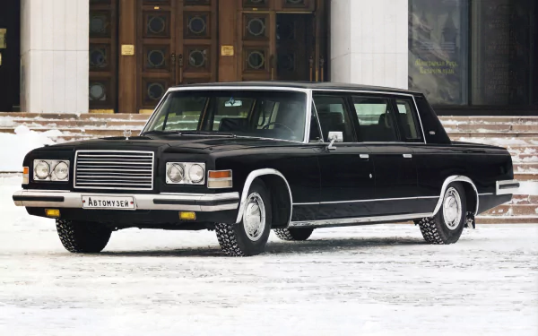 Black ZIL-41047 limousine parked on snow in front of a building — HD PC desktop wallpaper/background of a classic black car and luxury vehicle.
