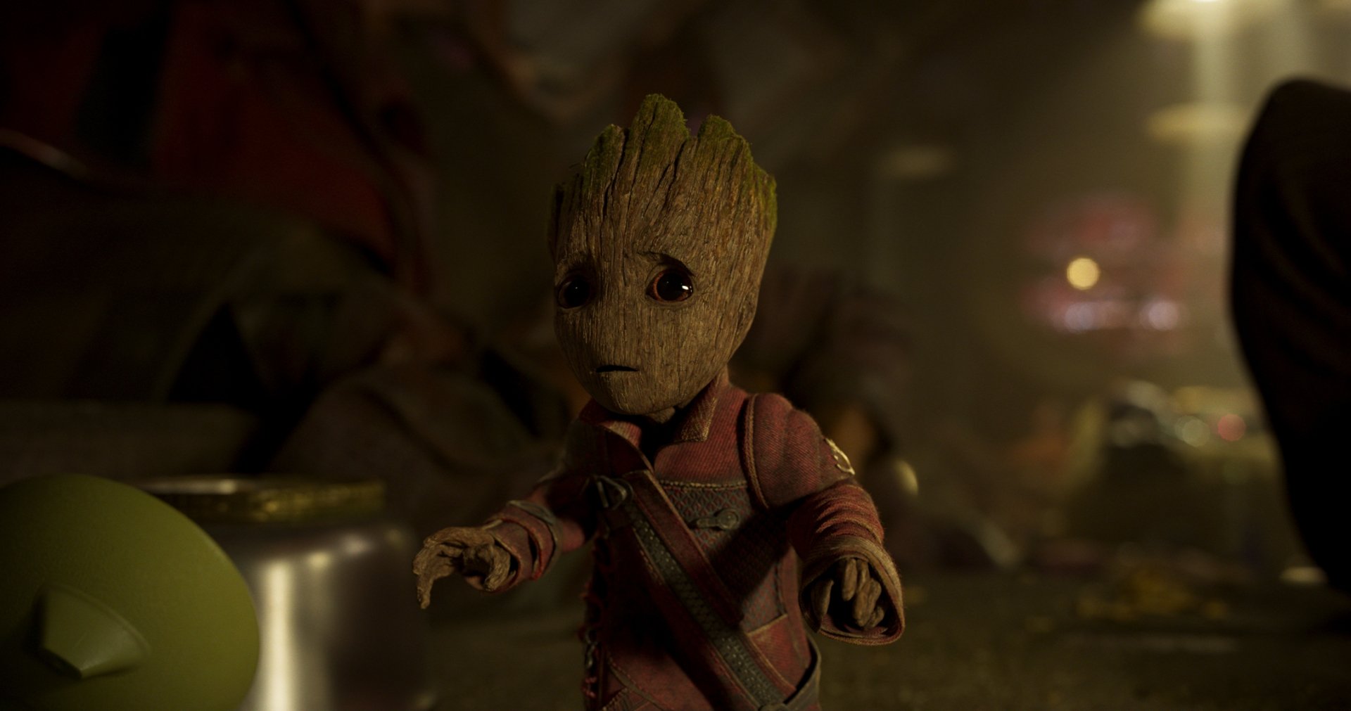 HD desktop wallpaper featuring Baby Groot from Guardians of the Galaxy Vol. 2. Baby Groot stands in a dimly lit environment, wearing his red outfit, showcasing the character's adorable expression and detailed texture.