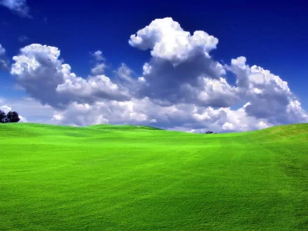 HD PC desktop wallpaper: vivid green rolling field beneath dramatic white clouds and a deep blue sky.