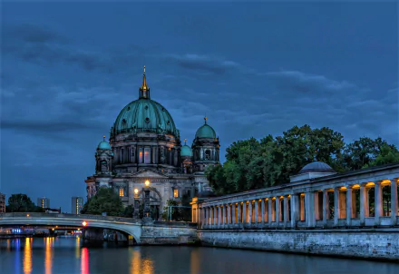 Berlin Cathedral with its illuminated dome stands by the river at dusk, framed by a lit bridge and twilight sky in this HD cityscape wallpaper.