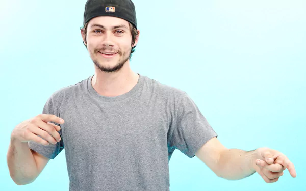 HD desktop wallpaper featuring a cheerful man in a gray t-shirt and a baseball cap against a light blue background.