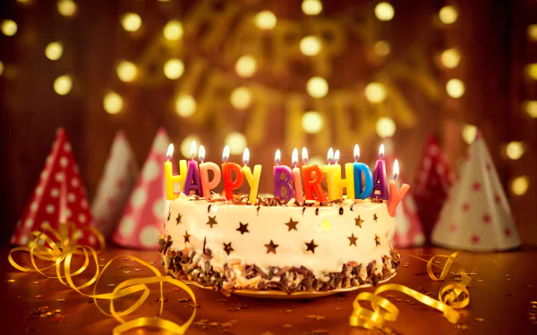 HD desktop wallpaper showing a festive birthday scene with a lit candle cake decorated with Happy Birthday letters, surrounded by colorful party hats and golden ribbons.