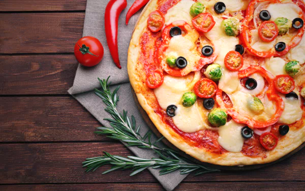 A vibrant 4K Ultra HD wallpaper featuring a fresh pizza topped with pepper, tomato, olives, and melted cheese on a wooden table with herbs and chili peppers.