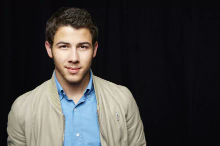 HD desktop wallpaper featuring a man in a beige jacket and blue shirt against a black background.