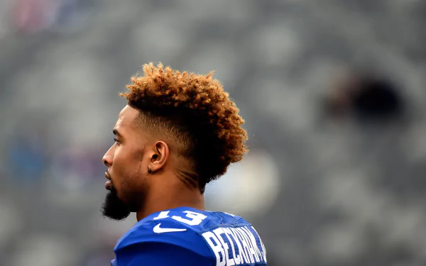 HD desktop wallpaper of a New York Giants player in blue jersey number 13, with the focus on his profile against a blurred stadium background.